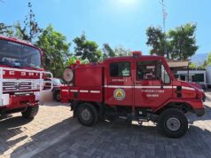 Waldbrandstufe 5 bei Athen: Unterwegs mit der Freiwilligen Feuerwehr Vyronas Zwei rote griechische Feuerwehrfahrzeuge mit der Aufschrift Vyronas stehen auf einem gepflasterten Hof