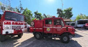 Waldbrandstufe 5 bei Athen: Unterwegs mit der Freiwilligen Feuerwehr Vyronas Zwei rote griechische Feuerwehrfahrzeuge mit der Aufschrift Vyronas stehen auf einem gepflasterten Hof