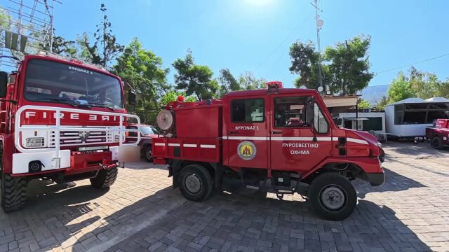 Zwei rote griechische Feuerwehrfahrzeuge mit der Aufschrift Vyronas stehen auf einem gepflasterten Hof