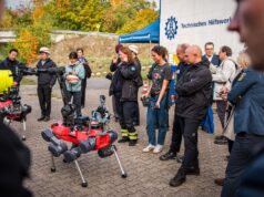Roboter, Sensoren, Ortung ohne GPS: THW-geführtes EU-Projekt SYNERGISE zeigt Ergebnisse in Berlin Zwei rote vierbeinige Roboter mit Kameras und Greifarm, umringt von Besuchern und Einsatzkräften, im Hintergrund ein THW-Zelt.