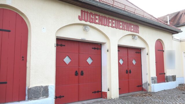 Fassade eines Feuerwehrhauses mit roten Holztoren.