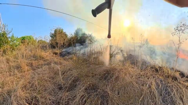 Serbien Vegetationsbrand Standbild Strahlrohr im Gegenlicht mit Wasserstrahl vor Rauch und Flammen